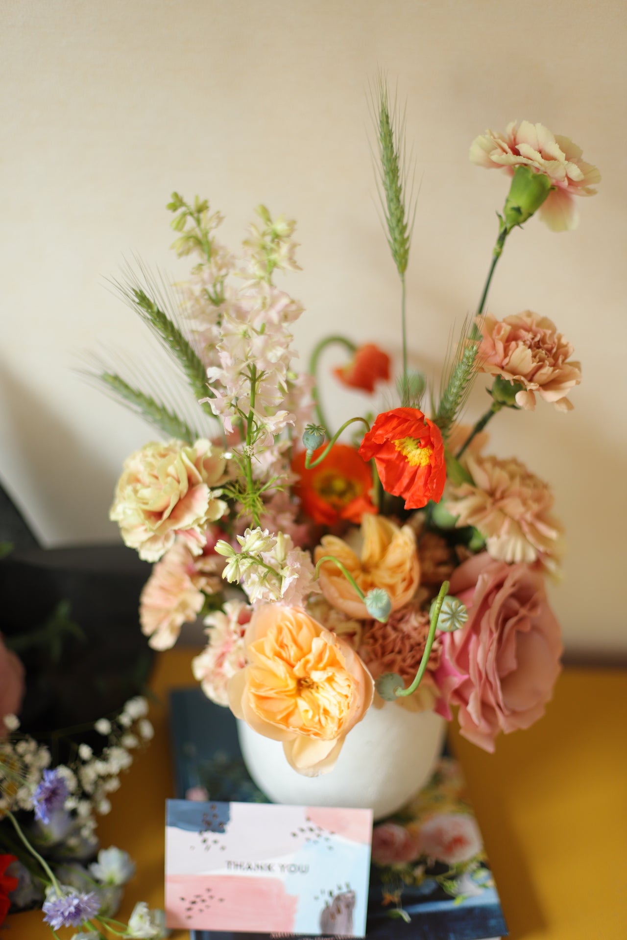 arrangement of peach, terra cotta, and orange flowers designed in a concrete vase